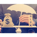 Man sitting with a scale with blocks on one side spelling RISK and a money bag with dollar symbol on it and his hand holding an umbrella