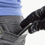 Hand in black glove grabbing phone out of back pocket of someone