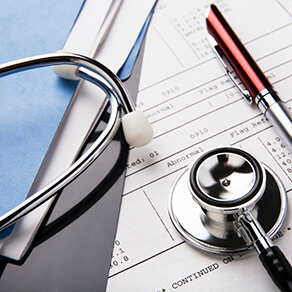 stethoscope and pen resting on a sheet of medical lab test results, with patient file and x-ray