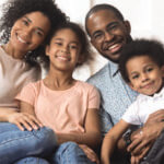 Family of four sitting together and smiling for a photo
