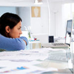 Lady looking at a laptop with a serious face - black hair and blue shirt